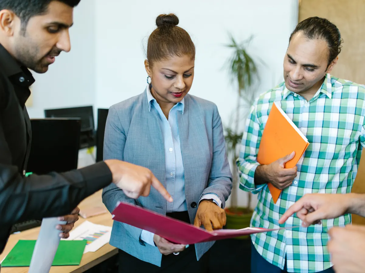 Small team reviewing documents together in an open-plan office, representing how a digital marketing agency plans its work