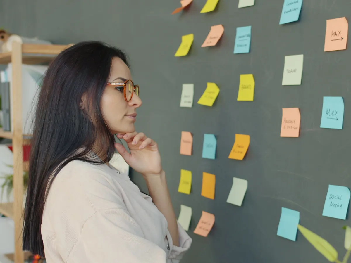Content strategist studying a wall of color-coded sticky notes while planning topics