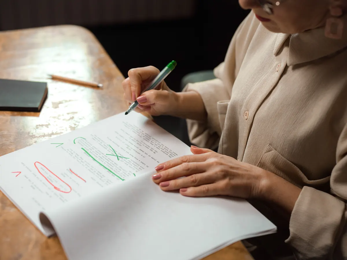 Editor marking up a printed article draft with green and red pen corrections