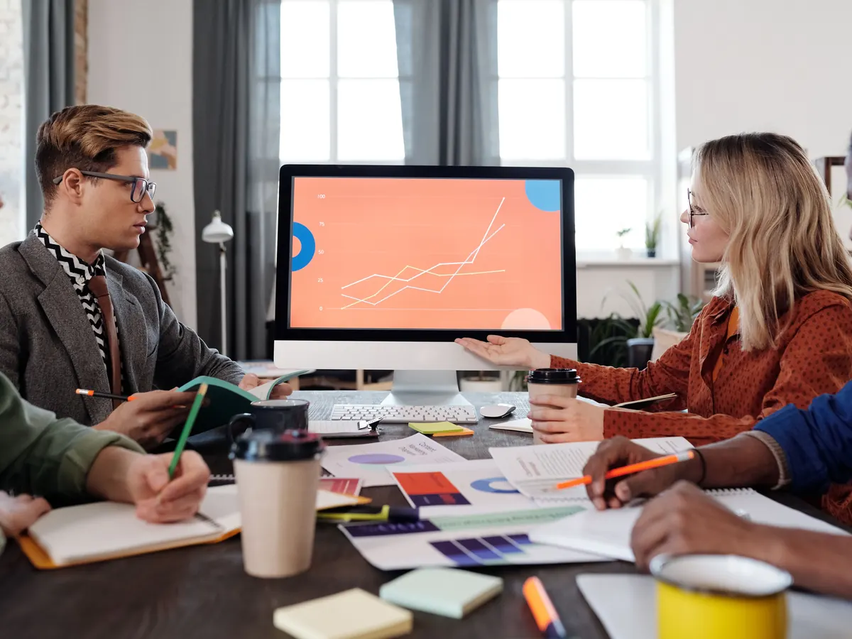 Marketing team discussing a performance chart on a desktop monitor, representing the work of an SEO and web development agency