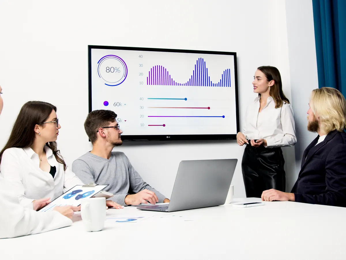 Marketing team reviewing the results of digital marketing services on a wall-mounted screen during a meeting