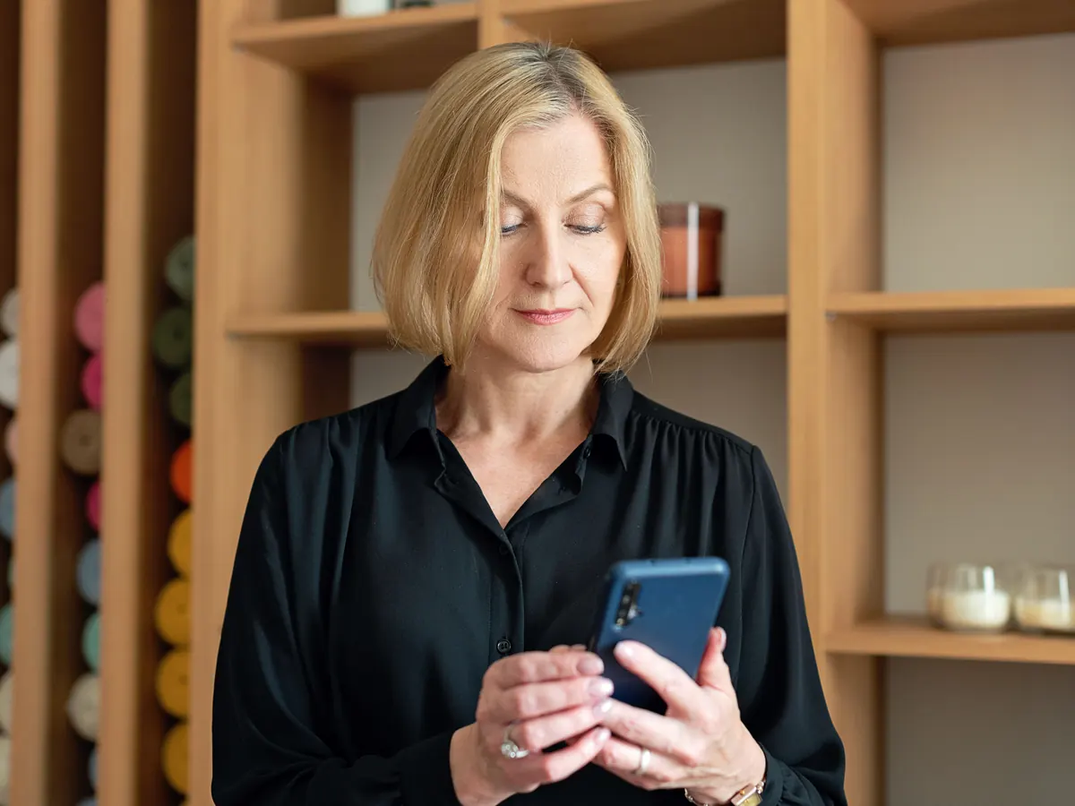 Online reputation management services start with what customers see: a business owner reading her phone beside wooden display shelves