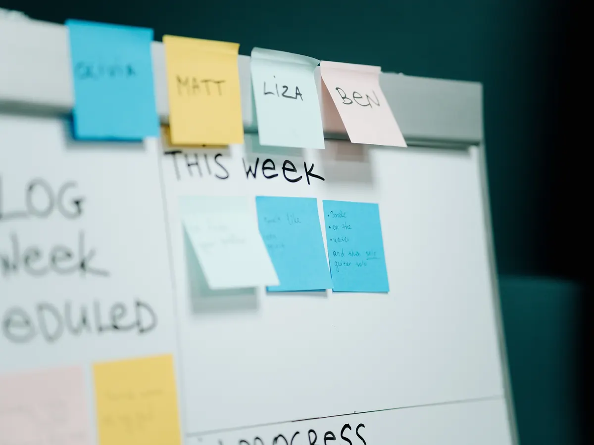 Sprint planning whiteboard with team names on sticky notes above a This Week column of task cards
